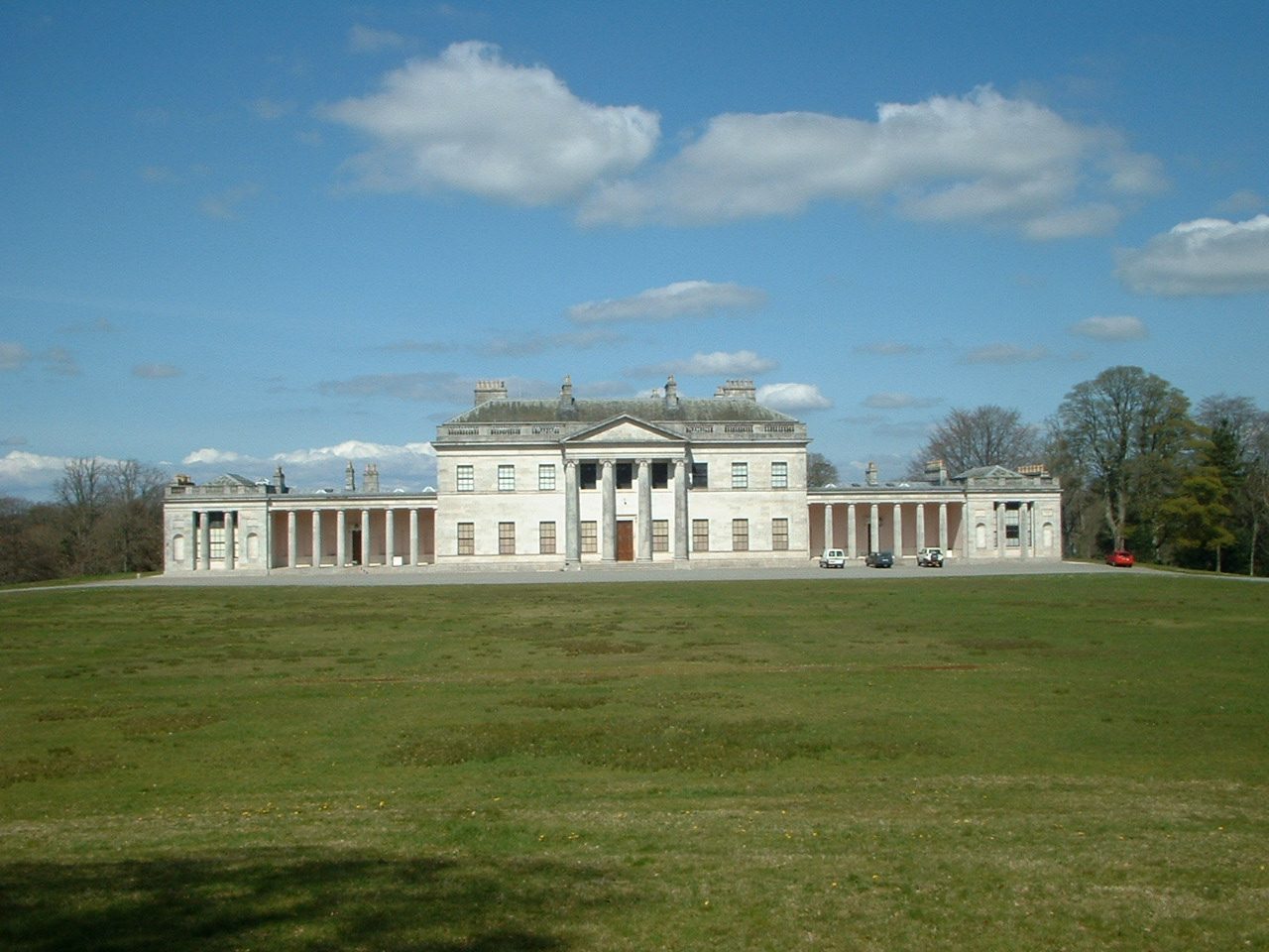 The neo-classical frontage of Castle Coole across open parkland on a bright day