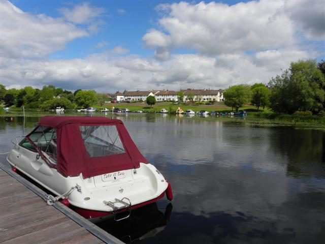 A small leisure boat moored at a wooden jetty on Lough Erne at Enniskillen on a bright day