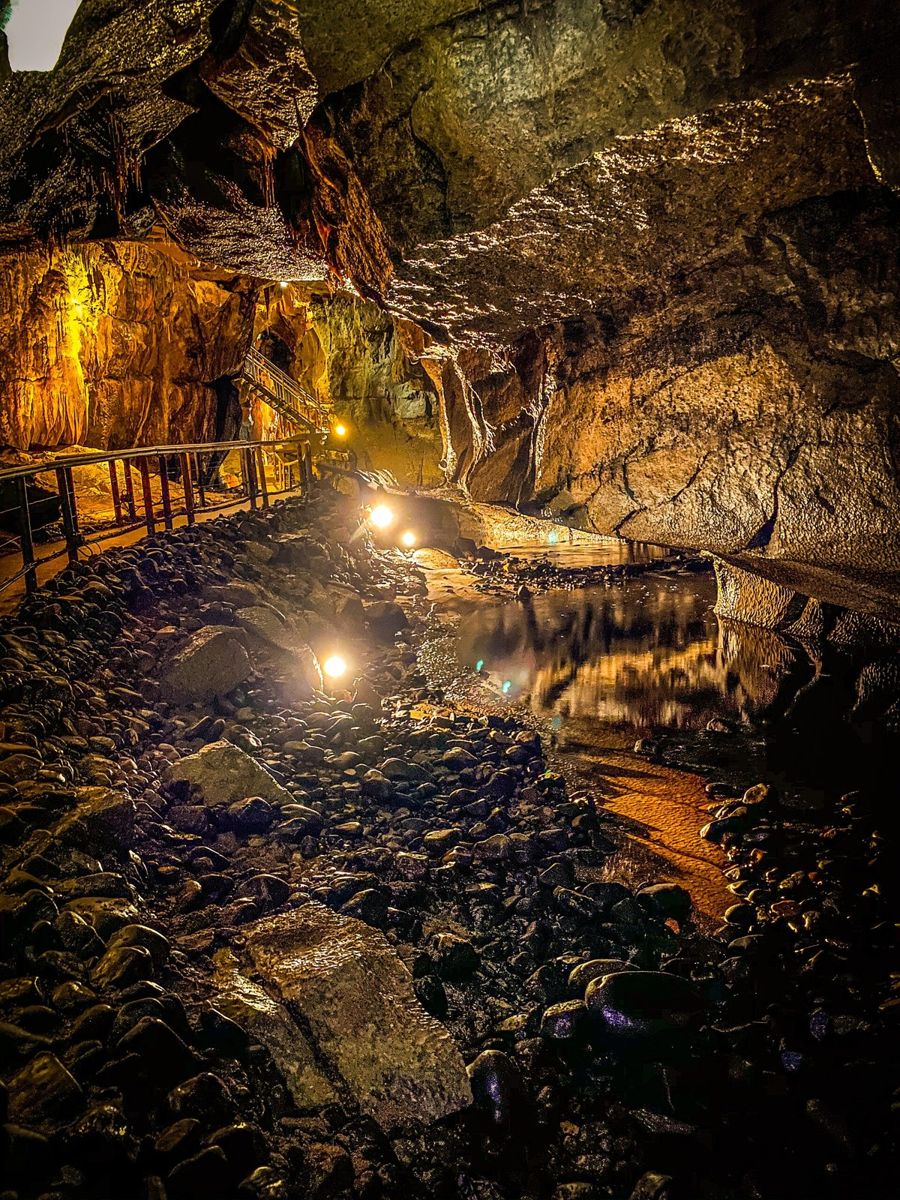 A lit underground chamber with flowstone formations inside Marble Arch Caves
